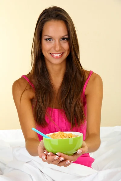 Ung vacker kvinna med skål med cornflakes i sängen — Stockfoto