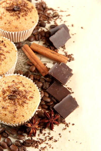 Tasty muffin cakes with chocolate, spices and coffee seeds, on beige backgr — Zdjęcie stockowe