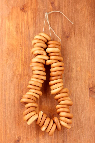 Tasty bagels on rope, on wooden background — Stock Photo, Image