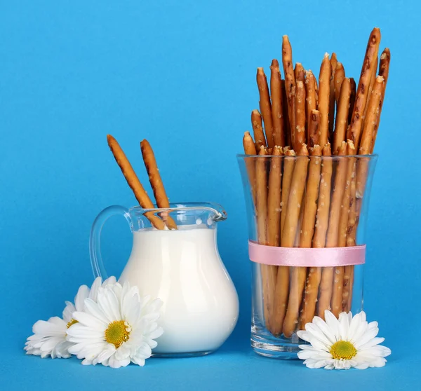 Leckere knusprige Sticks im Glasbecher auf blauem Hintergrund — Stockfoto