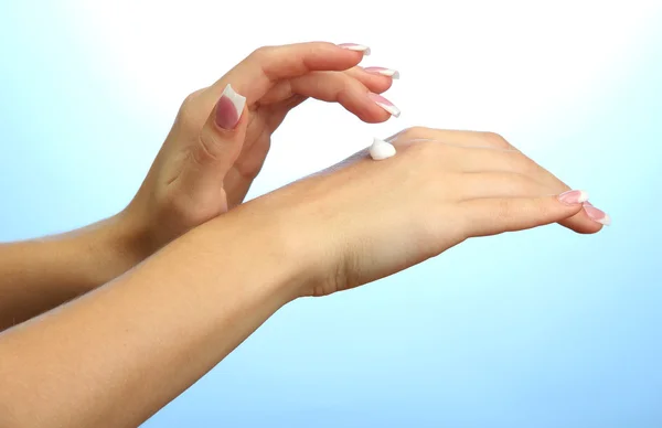 Beautiful woman hands with cream, on blue background — Stock Photo, Image