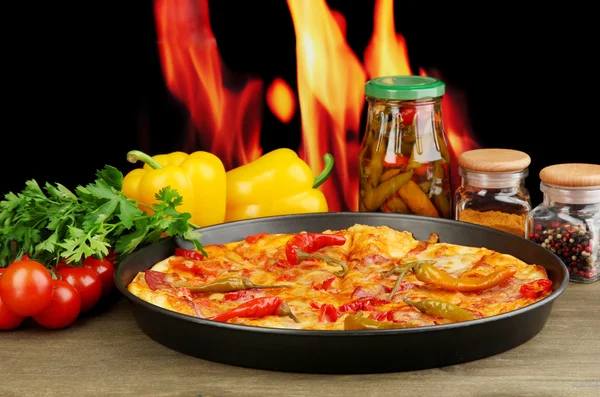 Tasty pepperoni pizza in pan with vegetables on flame background — Stock Photo, Image