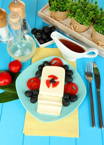 Queso feta en plato decorado con especias y aceite sobre tabla de madera azul clo —  Fotos de Stock