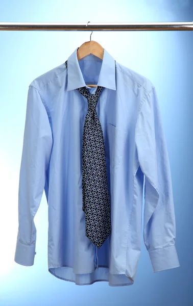 Shirt with tie on wooden hanger on blue background — Stock Photo, Image