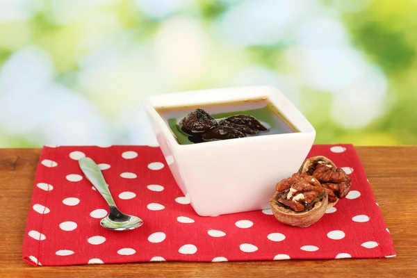 Marmelade Walnüsse in einer Schüssel auf einem Tisch auf grünem Hintergrund — Stockfoto