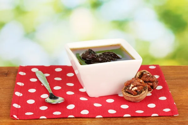 Jam walnuts in a bowl on a table on a green background — Stock Photo, Image