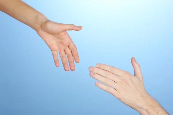 La mano de las mujeres va a la mano del hombre sobre fondo azul — Foto de Stock