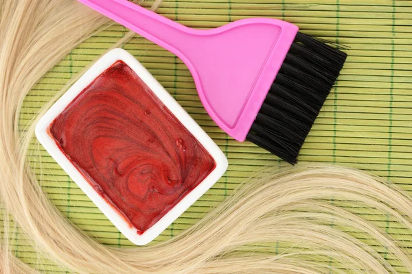 Tinte para el cabello en un tazón y cepillo para la coloración del cabello en una esterilla de bambú verde, primer plano — Foto de Stock