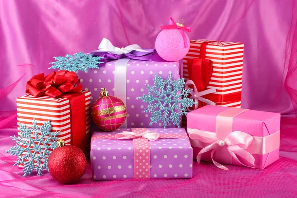 Mor, kırmızı ve pembe renkli hediyeler Noel topları ve kar tanesi üzerinde — Stok fotoğraf