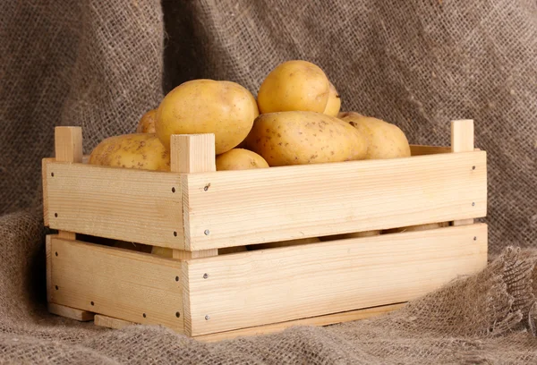 Ripe potatoes in wooden box on sacking — Stock Photo, Image