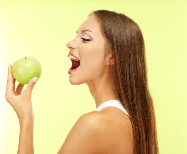 Bela jovem com maçã verde, no fundo verde — Fotografia de Stock