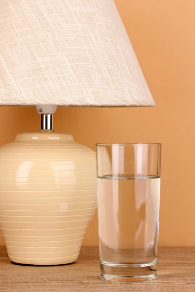 Asztali lámpa és a pohár vizet bézs háttér — Stock Fotó