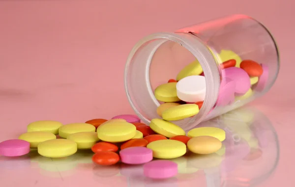 Comprimidos em recipiente sobre fundo vermelho — Fotografia de Stock