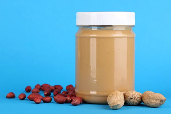 Delicious peanut butter in jar of peanut near on blue background — Stock Photo, Image