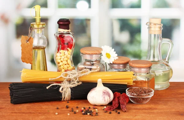 Pasta spaghetti, vegetables and spices on wooden table on bright background — Stock Photo, Image