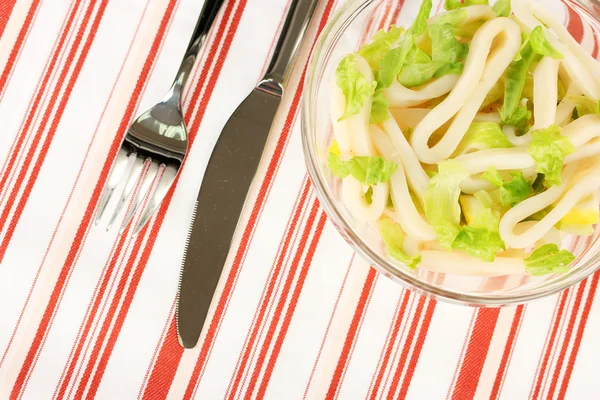 Salad of squid rings, lemon and lettuce in a glass bowl on striped tableclo — Stock Photo, Image