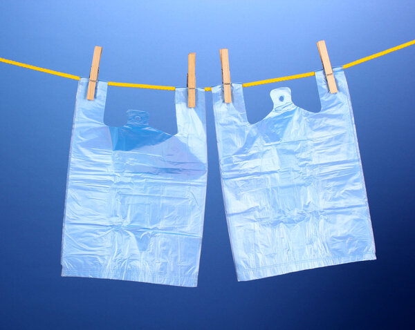 Целофановые мешки висят на веревке на синем фоне
