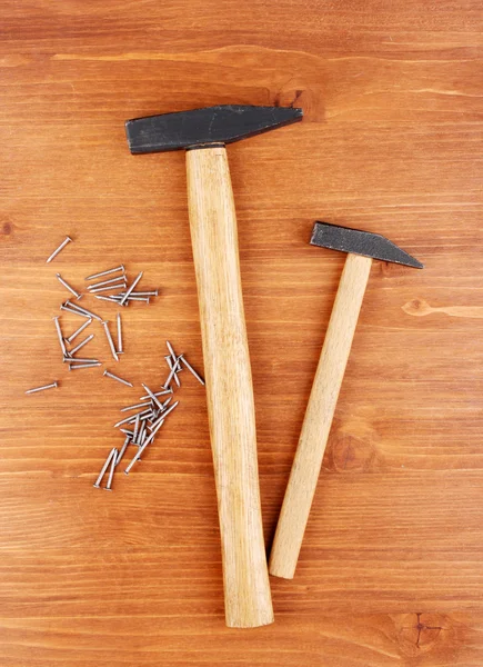 Martillos y clavos de metal sobre fondo de madera — Foto de Stock