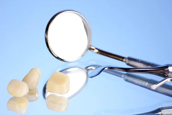 Espejo dental con dentadura postiza sobre fondo azul —  Fotos de Stock