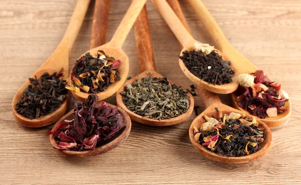 Assortment of dry tea in spoons, on wooden background — Stock Photo, Image