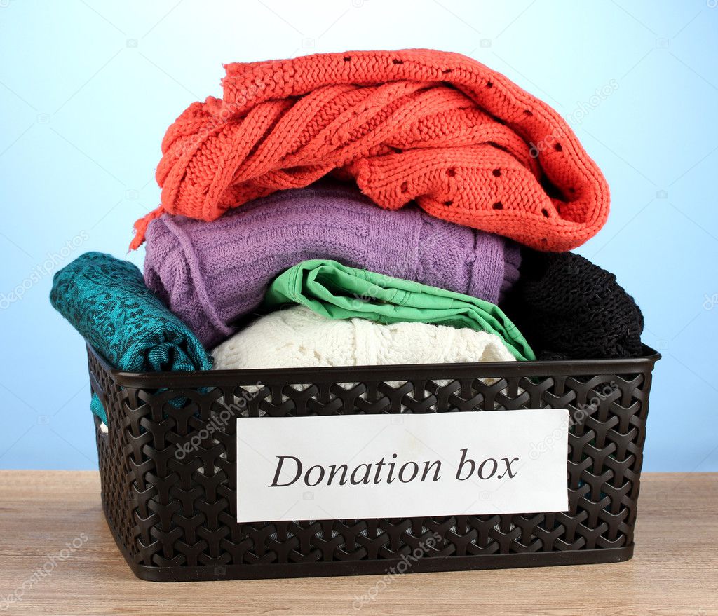 Donation box with clothing on blue background close-up