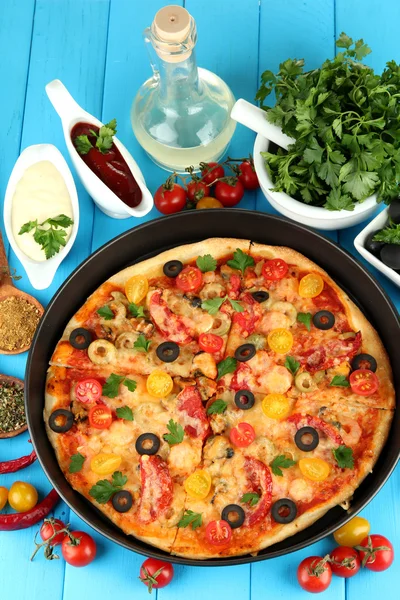 Colorful composition of delicious pizza, vegetables and spices on blue wood — Stock Photo, Image