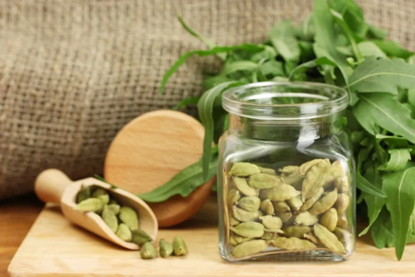 Jar of green cardamom with rocket on canvas background close-up — Stock Photo, Image