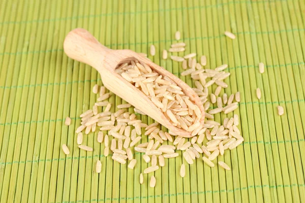 Rijst in houten lepel op bamboe mat — Stockfoto