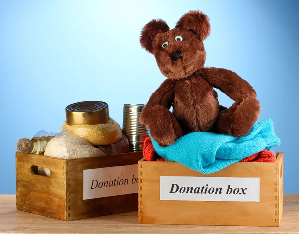 Cajas de donaciones con ropa y comida sobre fondo azul —  Fotos de Stock