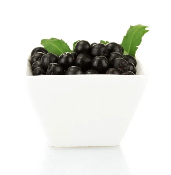 Chokeberry met groene bladeren in witte kom geïsoleerd op wit — Stockfoto