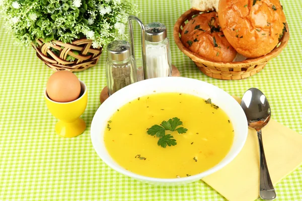 Ароматный суп в белой тарелке на зеленой скатерти крупным планом — стоковое фото