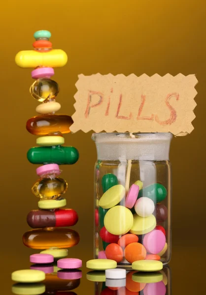 Kapslar och tabletter hill och i kärlet på gul bakgrund — Stockfoto