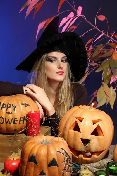 Хэллоуинская ведьма с тыквами на цветном фоне — стоковое фото