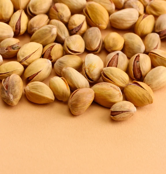 Smakelijke pistache noten, op beige achtergrond — Stockfoto