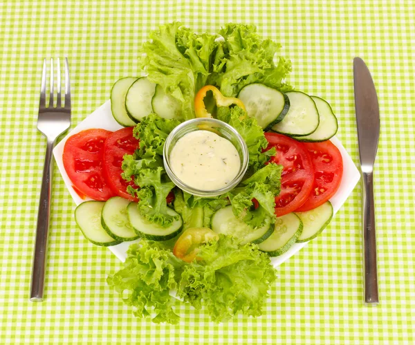 Ψιλοκομμένο λαχανικά και σάλτσα στο πιάτο στο πράσινο τραπεζομάντιλο — Φωτογραφία Αρχείου