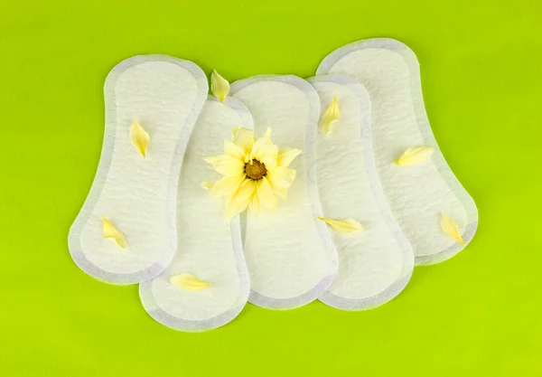 Daily panty liners and yellow flower on green background close-up — Stock Photo, Image