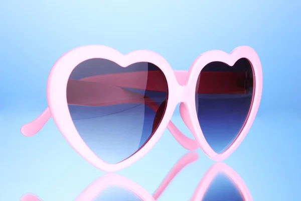 Gafas de sol rosadas en forma de corazón sobre fondo azul — Foto de Stock