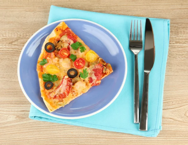 Assiette avec une tranche de délicieuse pizza sur fond en bois — Photo