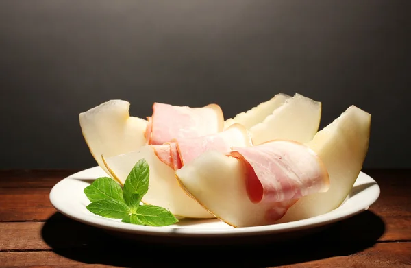 Parma ham and melon, on wooden table, on grey background — Stock Photo, Image