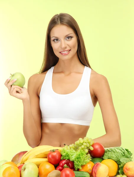 Gyönyörű fiatal nő, gyümölcsök és zöldségek, zöld háttér — Stock Fotó