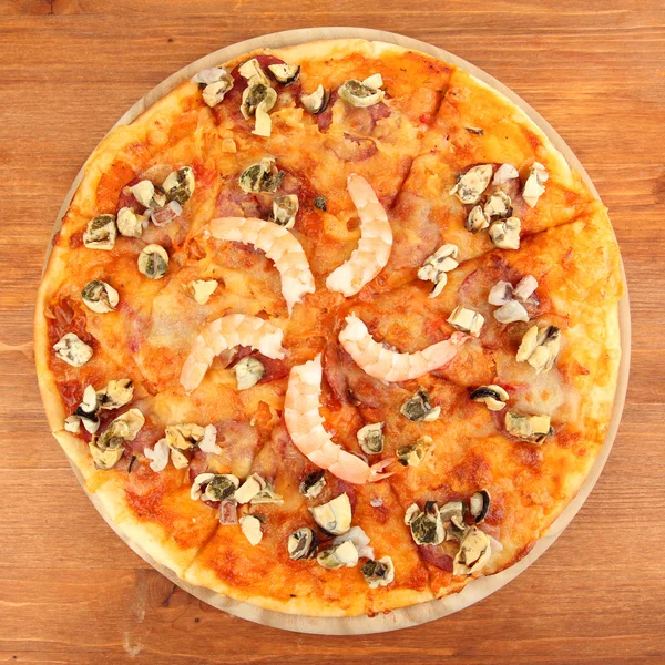 Ahşap arka plan üzerinde durmak üstünde deniz ürünleri ile lezzetli pizza — Stok fotoğraf