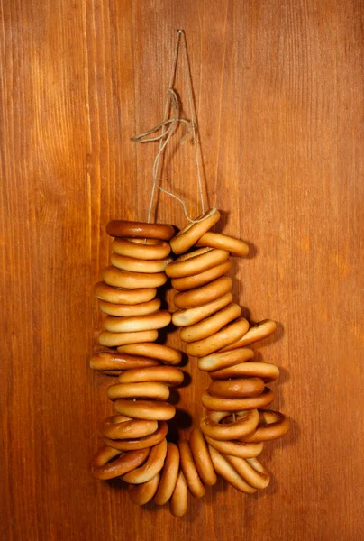 Tasty bagels on rope, on wooden background — Stock Photo, Image