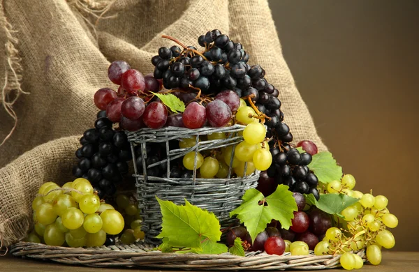 Sortiment av mogna söta druvor i korg, på brun bakgrund — Stockfoto