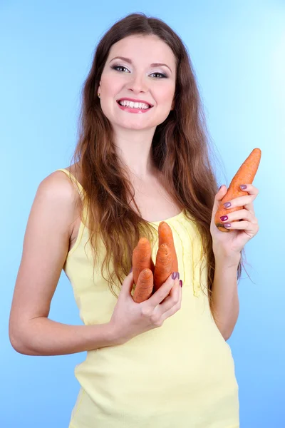Bella donna con carota su sfondo blu — Foto Stock