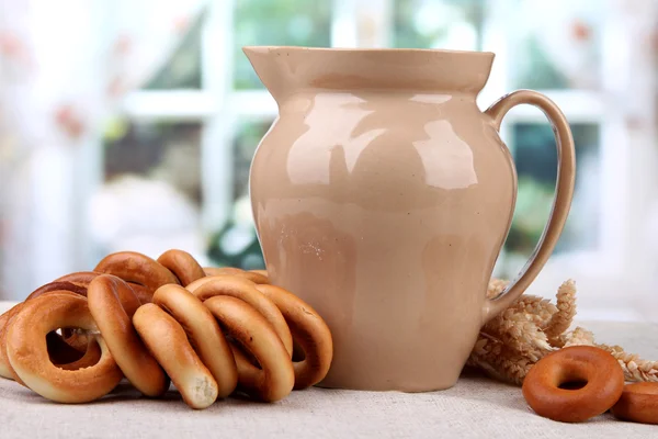 Jar of milk, tasty bagels and spikelets on table — Stock Photo, Image