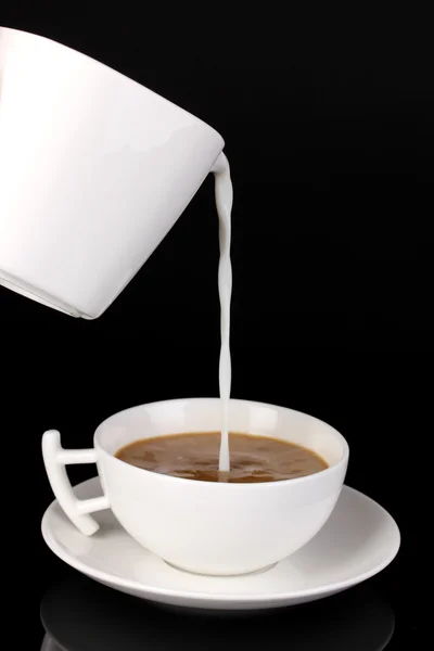 Jemnou smetanou nalije do šálku kávy izolovaných na černém — Stock fotografie