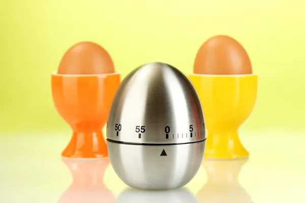 Temporizador de huevo y huevo en color de pie sobre fondo verde —  Fotos de Stock