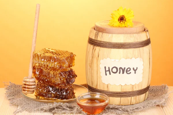 Baril de miel et nid d'abeille sur table en bois sur fond orange — Photo