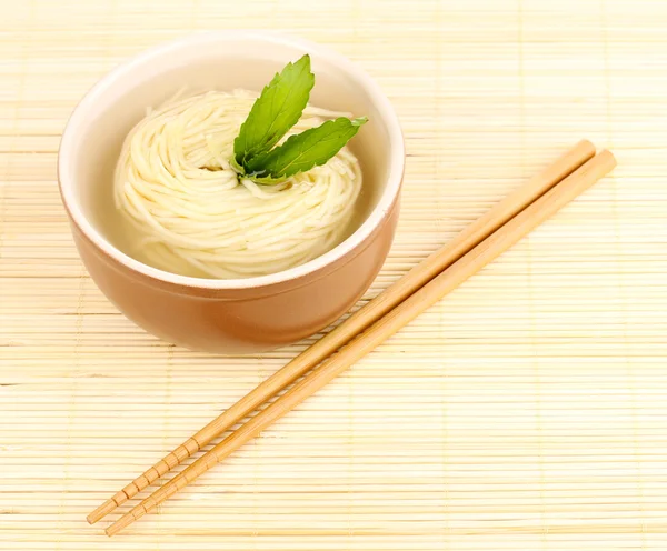 Asian noodles in bowl on bamboo mat — Stock Photo, Image