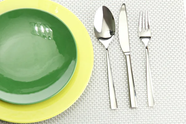 Assiettes vides vertes avec fourchette, cuillère et couteau sur une nappe grise — Photo